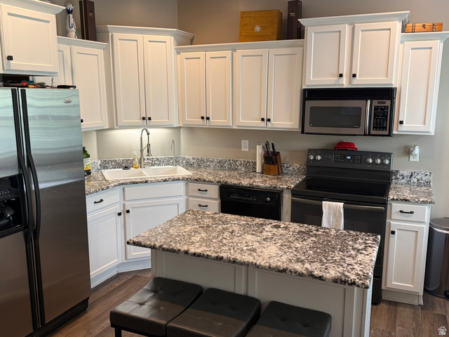 14797 South Chandlerpoint Way Draper, UT 84020 - Photo 7 of 33 Modern kitchen featuring white shaker cabinetry, speckled countertops, stainless steel appliances, a corner sink, and wood-finish flooring