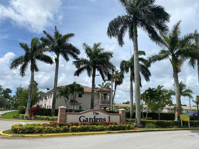 a front view of multi story residential apartment building with yard and sign board