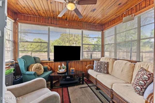 a living room with furniture a flat screen tv and a floor to ceiling window