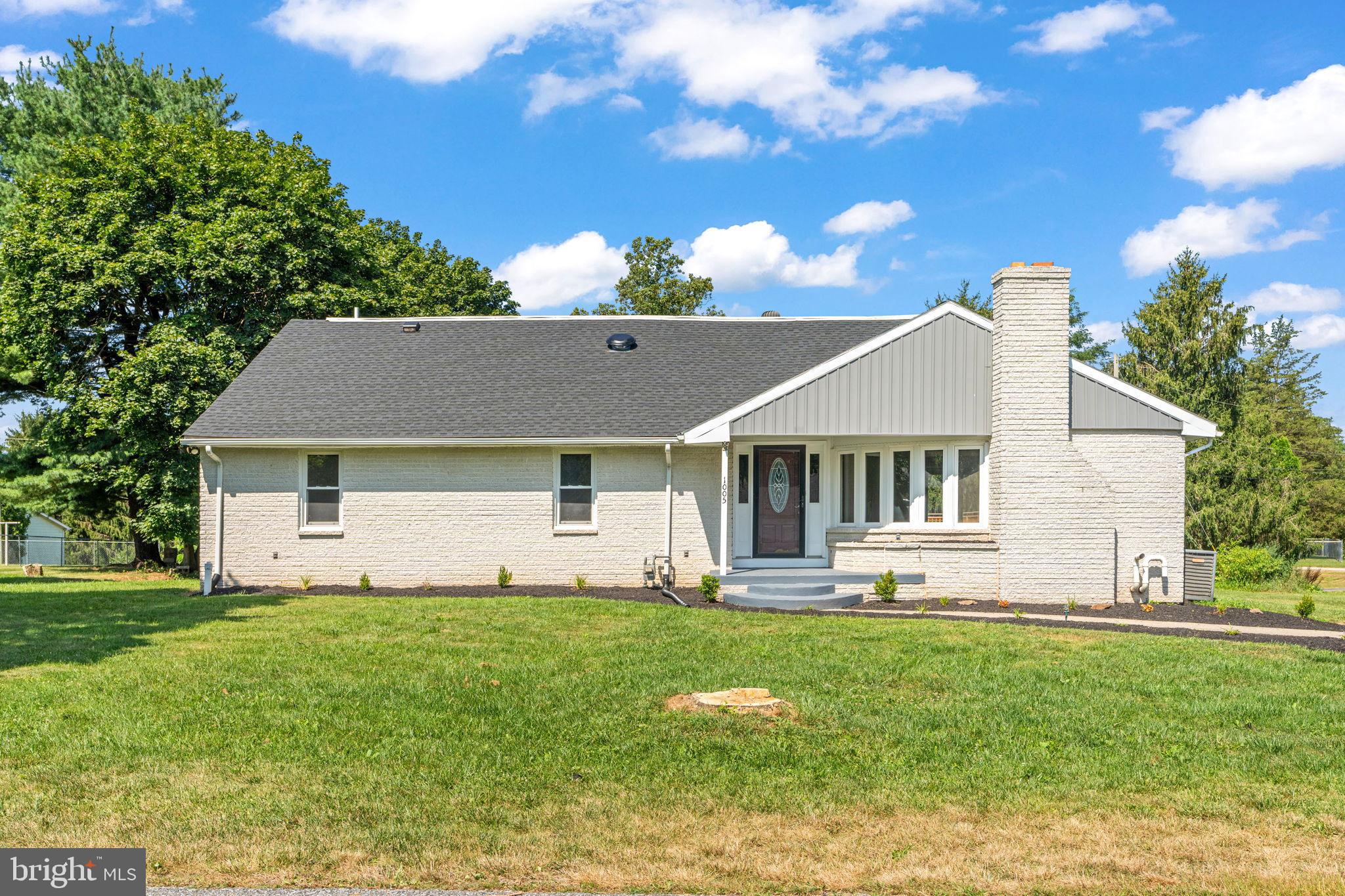 a front view of house with yard and trees in the background