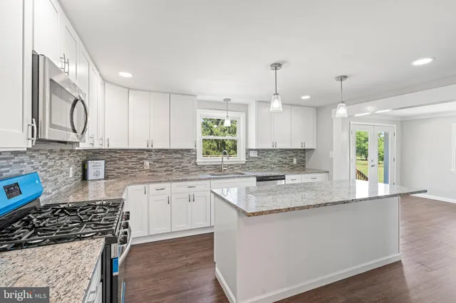 a kitchen with granite countertop a sink a counter top space stainless steel appliances and cabinets