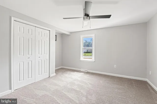 a view of empty room with window and ceiling fan