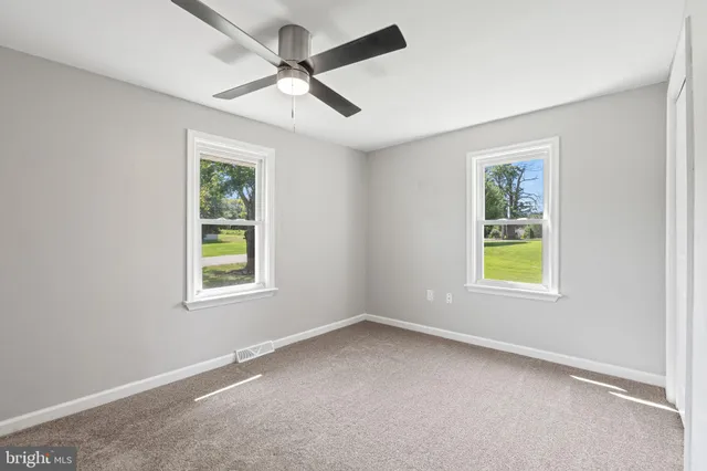 an empty room with windows and fan