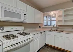 a kitchen with white cabinets and appliances