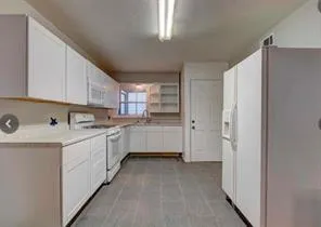 a kitchen with white cabinets and white appliances