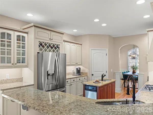 a kitchen with stainless steel appliances granite countertop a refrigerator a stove and a sink