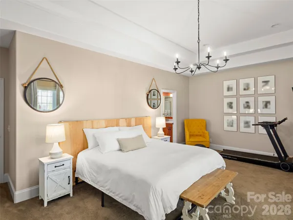 a bed room with a bed mirror and a chandelier