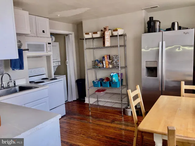 a kitchen with stainless steel appliances a stove a refrigerator a sink a counter space and wooden floor