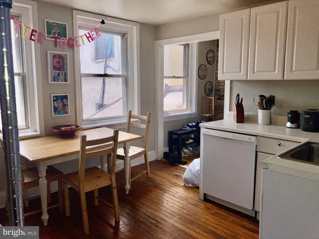 a kitchen with stainless steel appliances white cabinets and wooden floor