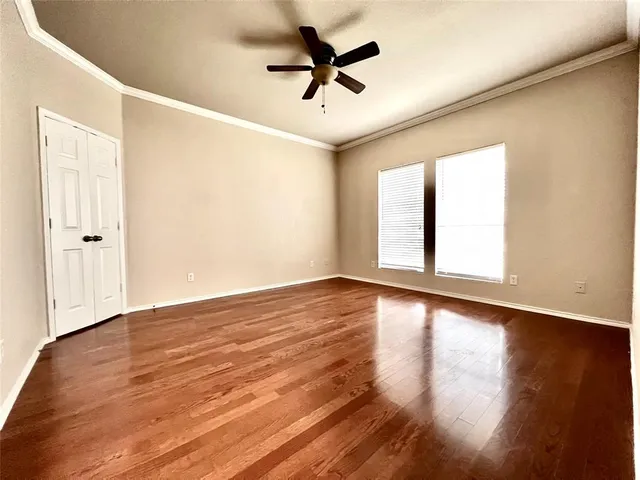 an empty room with wooden floor and windows