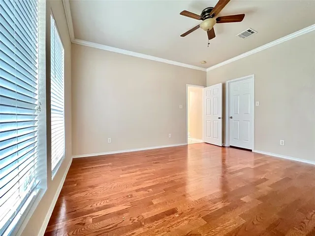 a view of empty room with wooden floor and fan