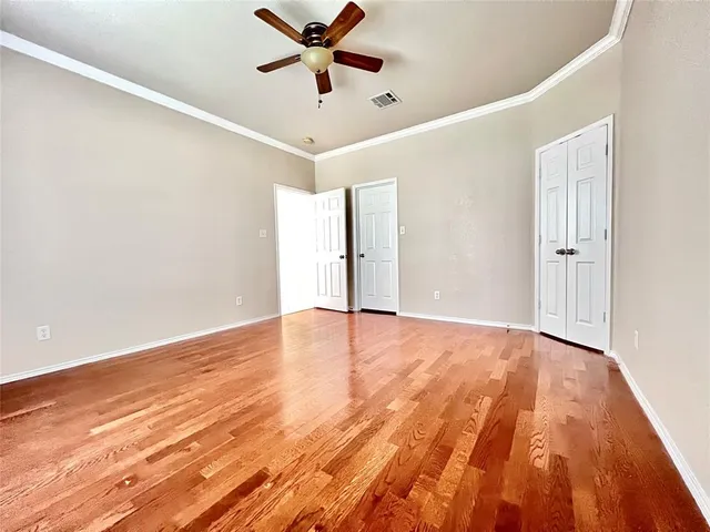 an empty room with wooden floor fan and windows