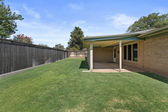 a view of backyard with small cabin and wooden fence
