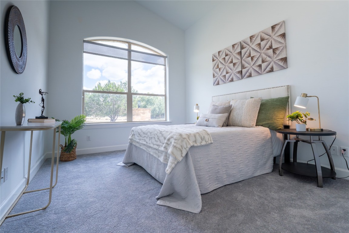 724 Chama Trace Dripping Springs, TX 78620 - Photo 18 of 40 a bedroom with a bed table chair and a window