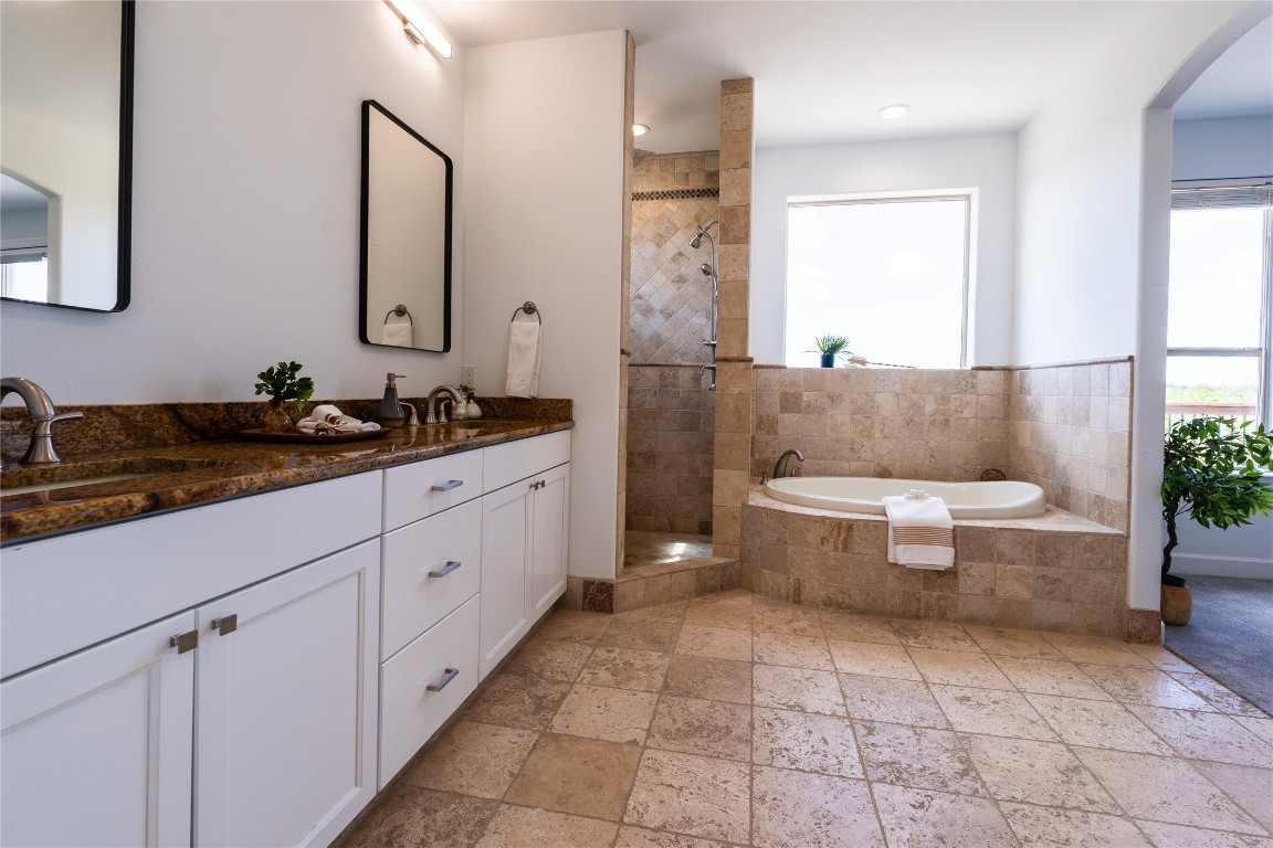 724 Chama Trace Dripping Springs, TX 78620 - Photo 29 of 40 a spacious bathroom with a double vanity sink a mirror and a bathtub