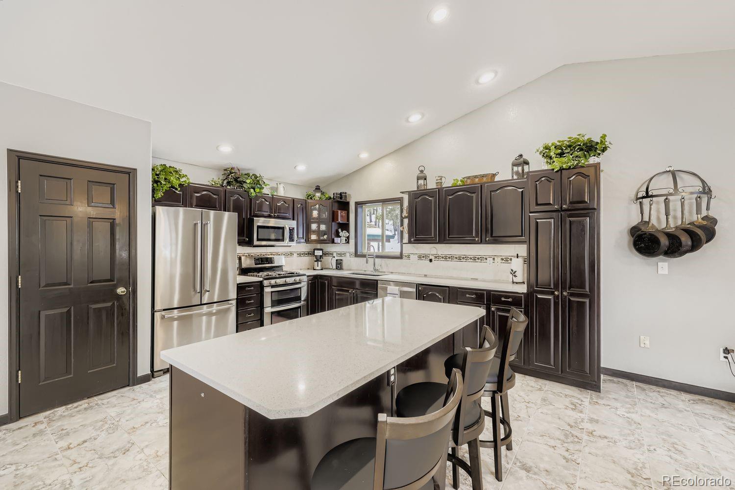 296 Desperado Road Bailey, CO 80421 - Photo 10 of 37 a kitchen with stainless steel appliances a dining table chairs and refrigerator
