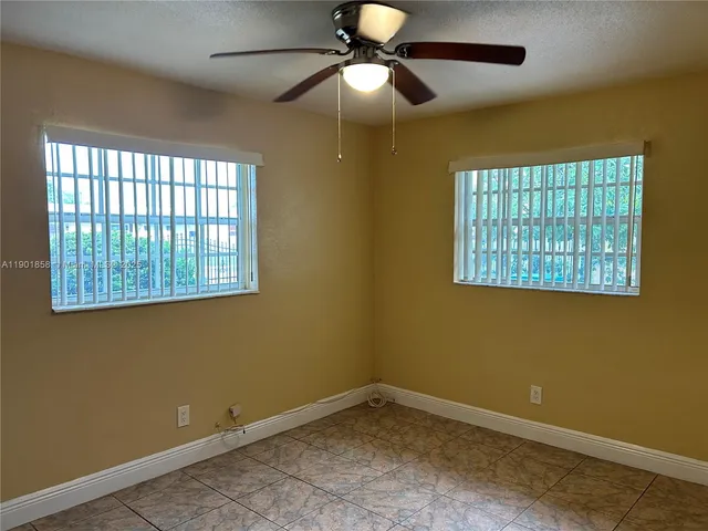 a view of an empty room with window and chandelier fan