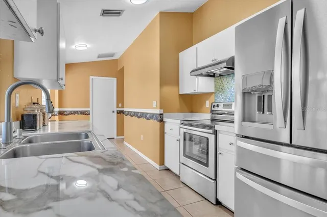 a kitchen with stainless steel appliances granite countertop a sink and a refrigerator