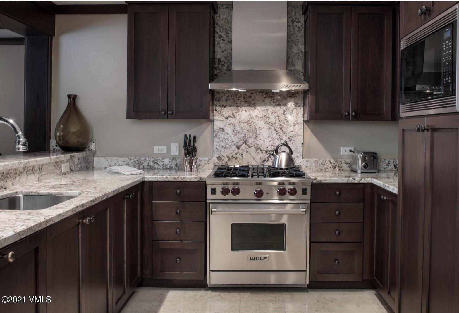 1 Vail Road, Unit 6102D Vail, CO 81657 - Photo 2 of 9 a kitchen with stainless steel appliances granite countertop a stove and a microwave