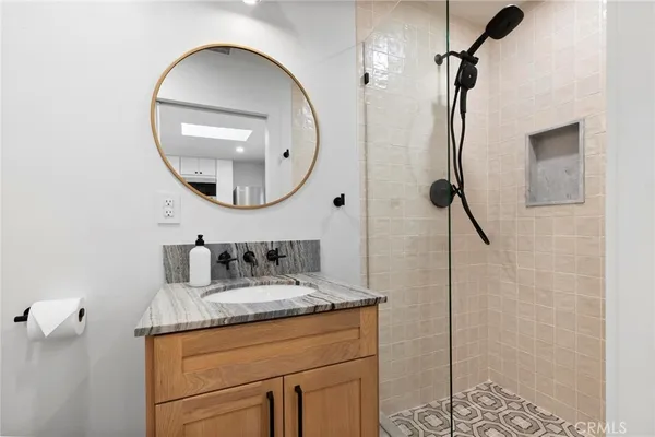 a bathroom with a granite countertop sink a mirror and shower