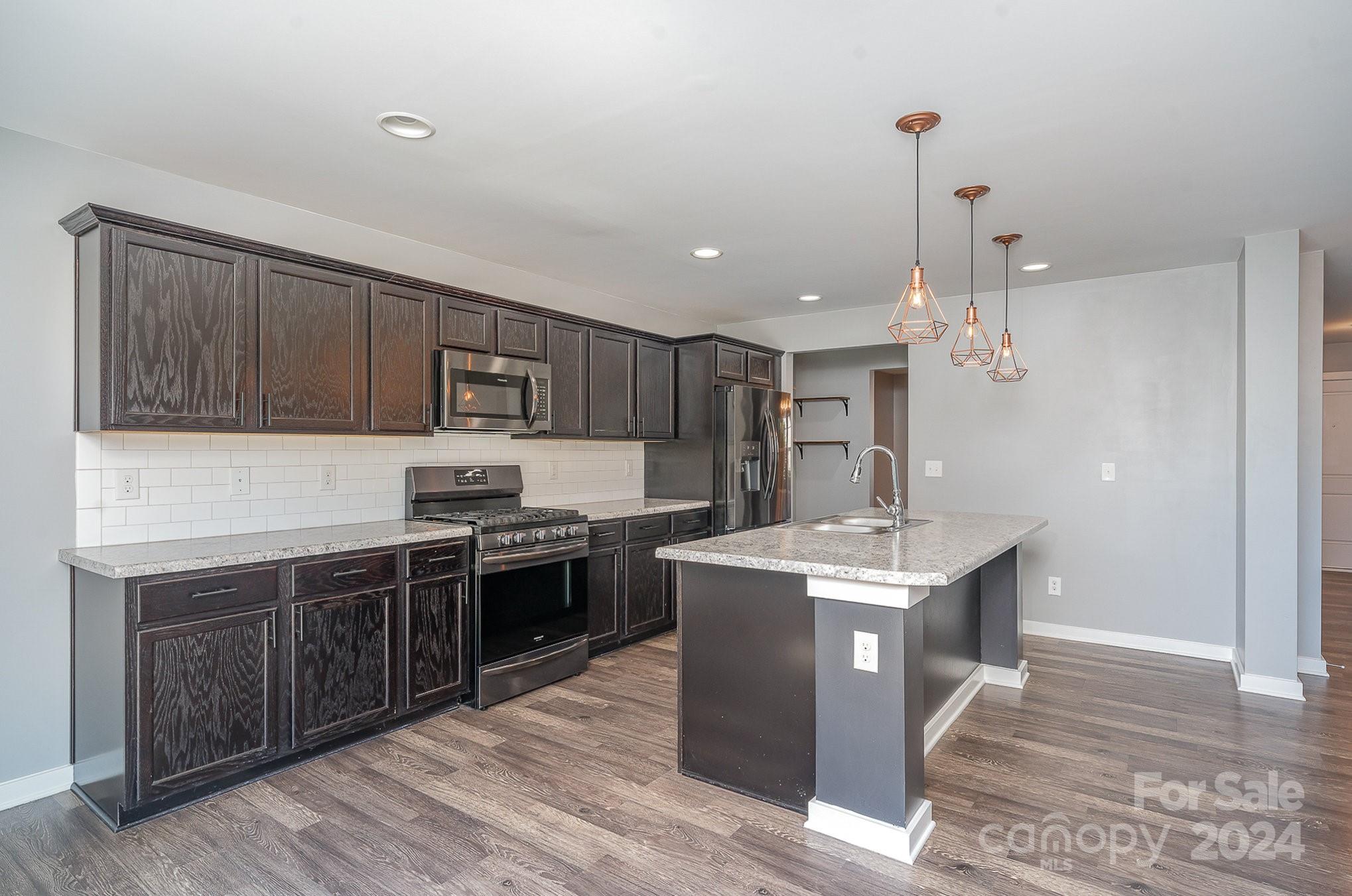 4602 Gibbons Link Road Charlotte, NC 28269 - Photo 9 of 35 a kitchen with stainless steel appliances granite countertop a stove top oven a sink dishwasher and a refrigerator with wooden floor