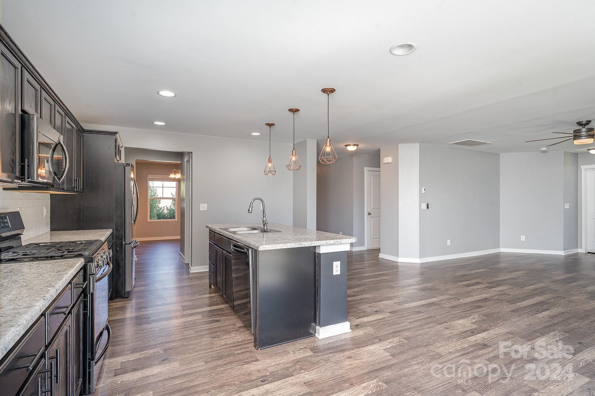 4602 Gibbons Link Road Charlotte, NC 28269 - Photo 10 of 35 a open kitchen with kitchen island a stove a sink dishwasher and a dining table with wooden floor