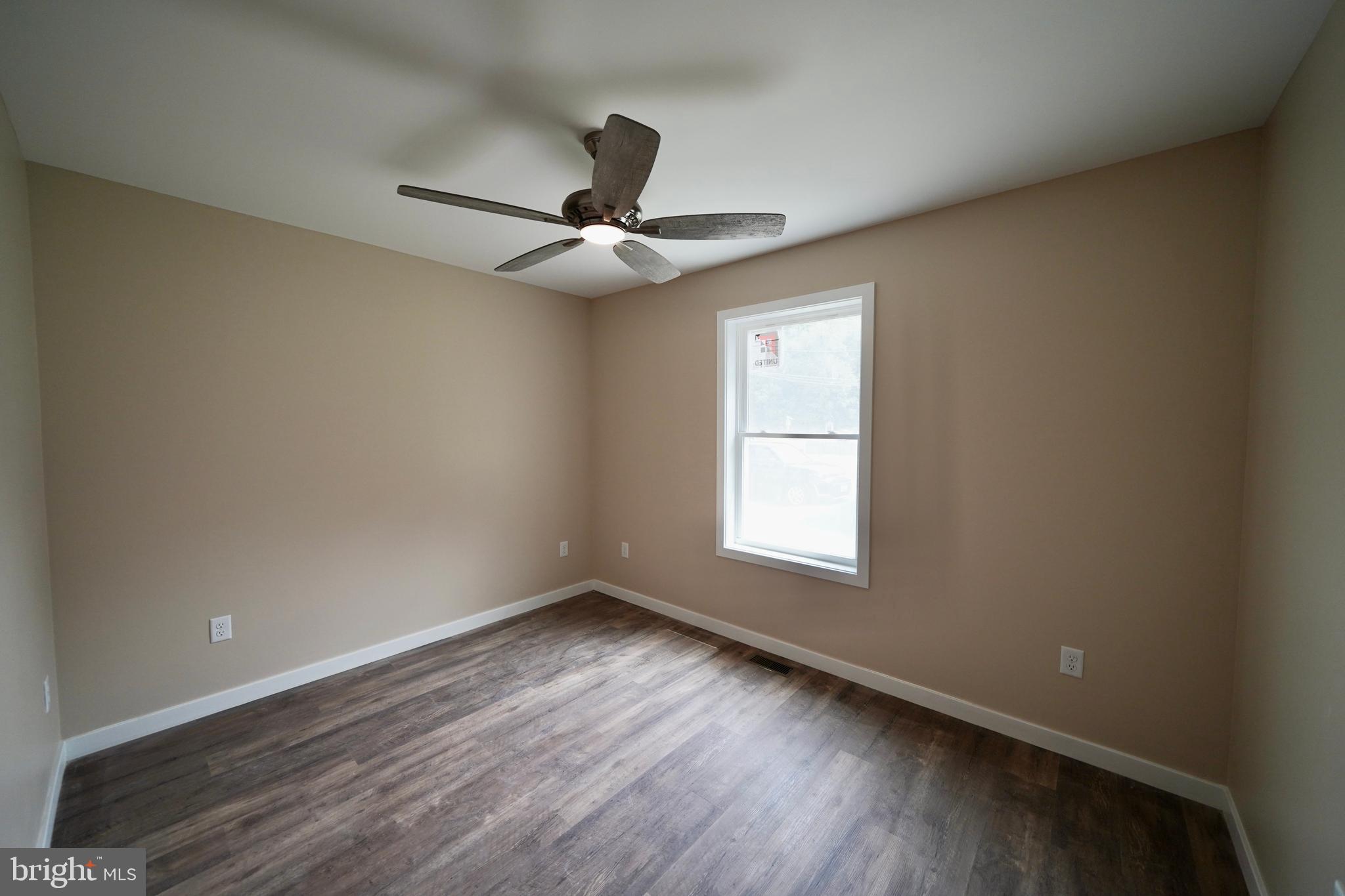 109 Main Street Ellendale, DE 19941 - Photo 14 of 29 an empty room with wooden floor ceiling fan and windows