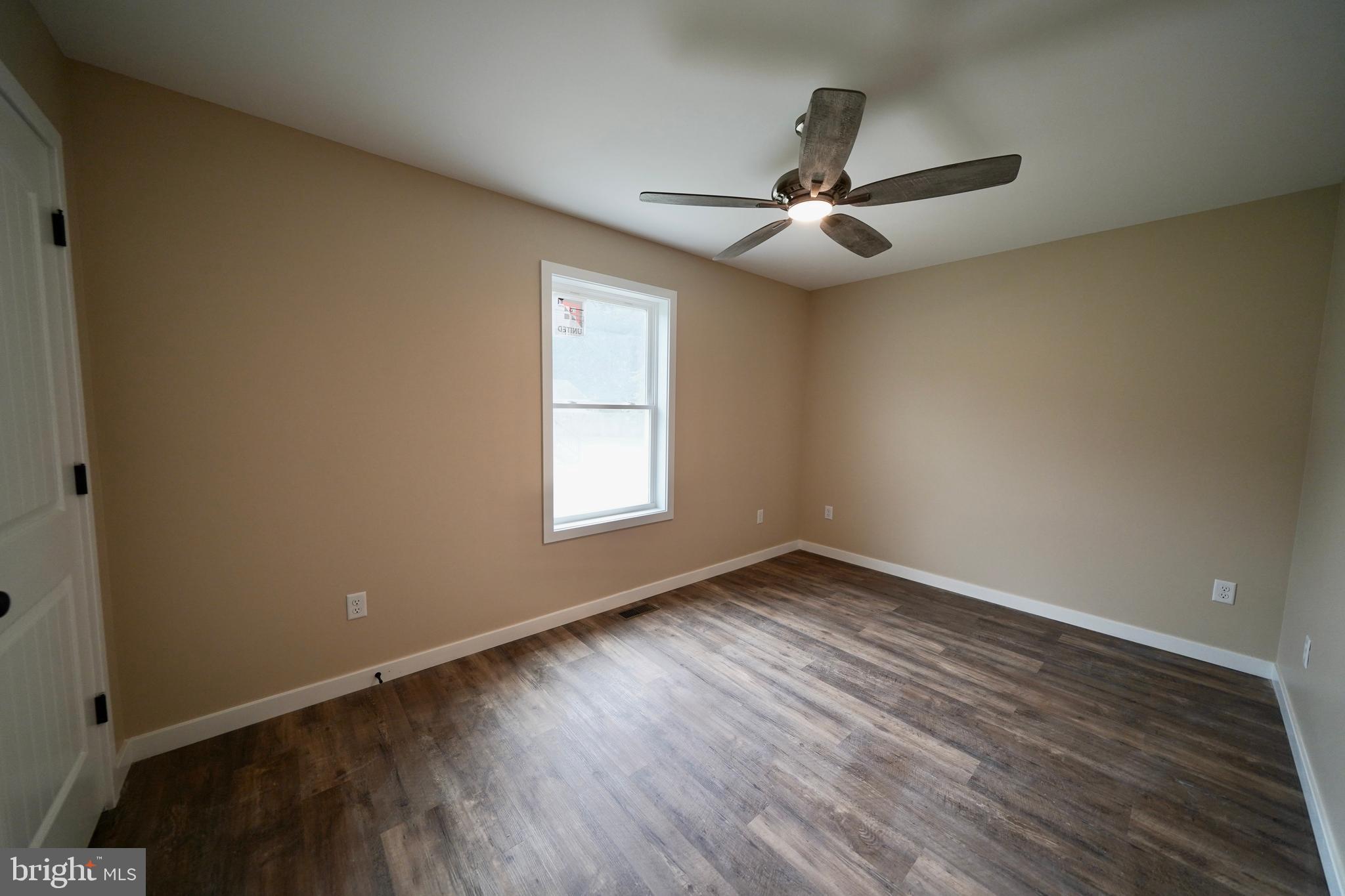 109 Main Street Ellendale, DE 19941 - Photo 17 of 29 an empty room with wooden floor a ceiling fan and windows