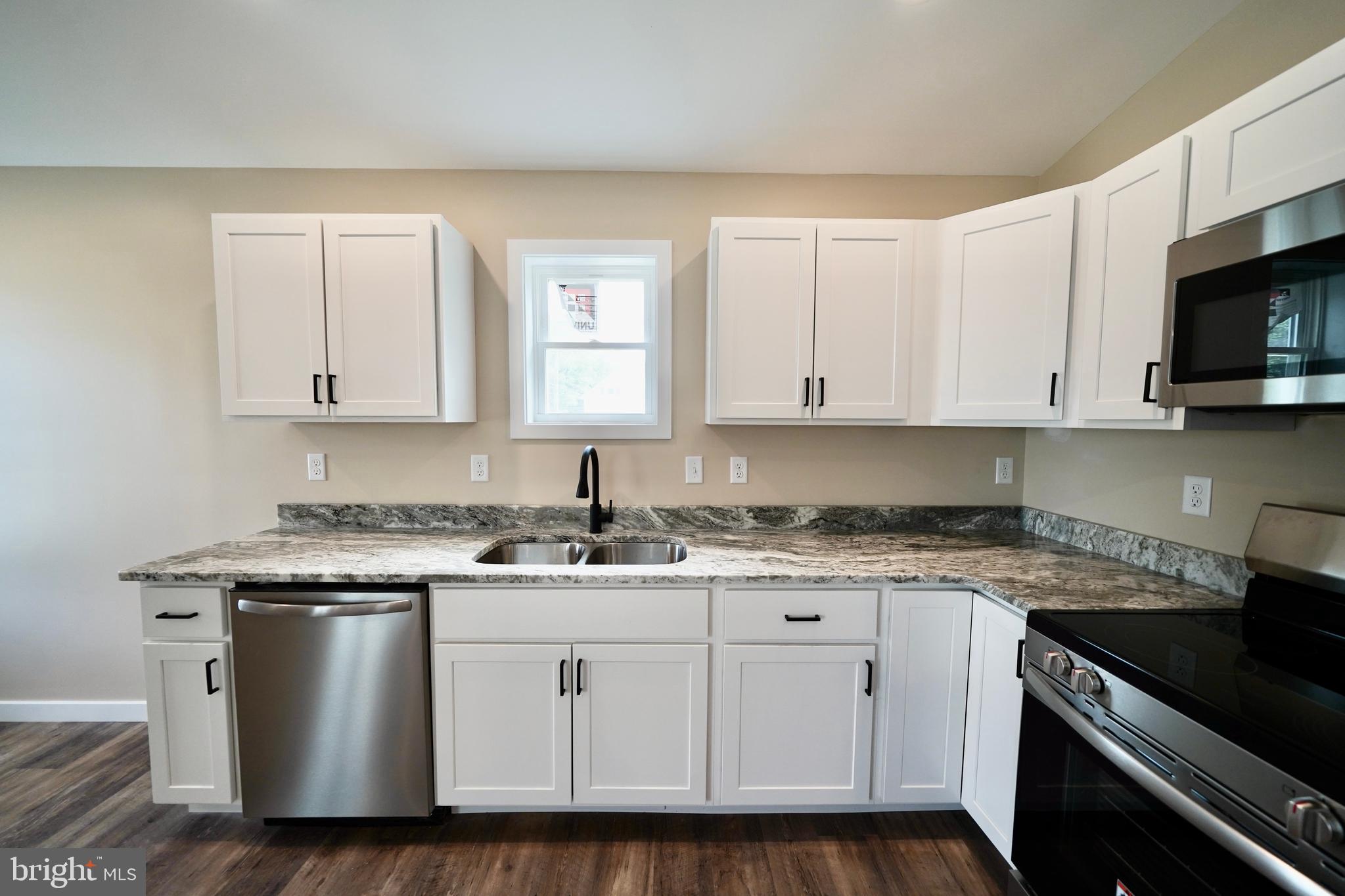 109 Main Street Ellendale, DE 19941 - Photo 10 of 29 a white kitchen with stainless steel appliances granite countertop a sink and a stove