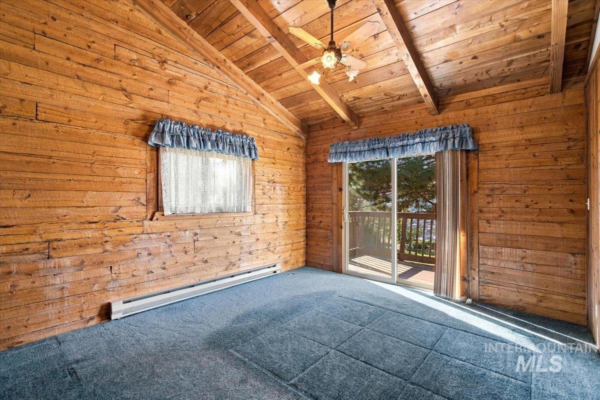 10201 Willis Road Middleton, ID 83644 - Photo 11 of 38 Vaulted wood-paneled ceiling, exposed wood beams, sliding glass door to exterior, ceiling fan, wood-paneled walls