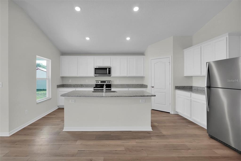 2 Prince Eric Lane Palm Coast, FL 32164 - Photo 8 of 24 a kitchen with stainless steel appliances granite countertop a stove a refrigerator a sink a microwave and white cabinets with wooden floor