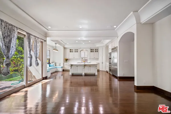 a living room with stainless steel appliances furniture a large window and wooden floor