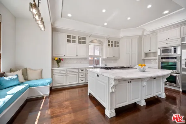 a large kitchen with kitchen island a sink stove and white cabinets