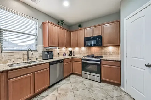 a kitchen with granite countertop a sink a window and cabinets