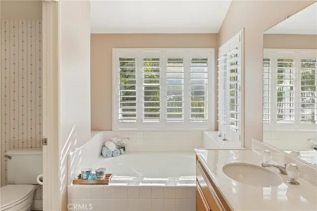 a bathroom with a granite countertop tub sink and a window