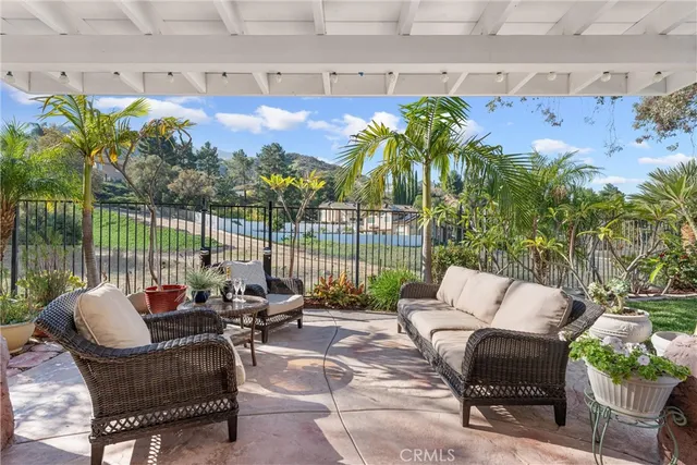 a balcony with couple of chairs and a potted plant