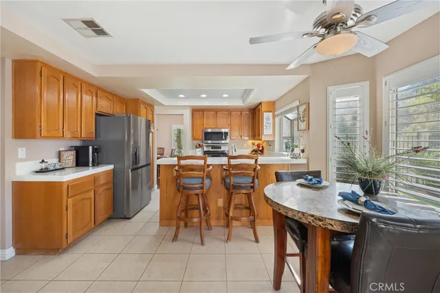 a kitchen with stainless steel appliances kitchen island granite countertop a table chairs and a refrigerator