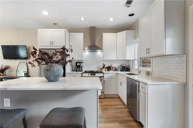 a kitchen with a sink dishwasher a stove a microwave oven and white cabinets