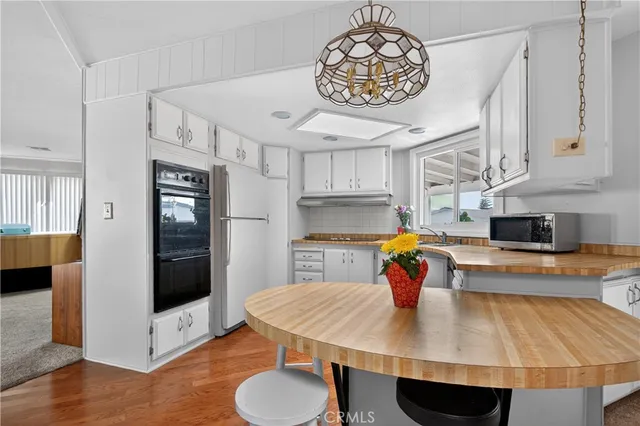 a kitchen with stainless steel appliances a table chairs and wooden floor