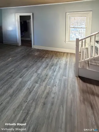 a view of an empty room with a window and wooden floor