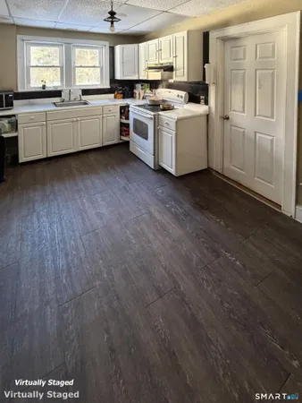 a kitchen with stainless steel appliances a sink a stove a refrigerator cabinets and a window