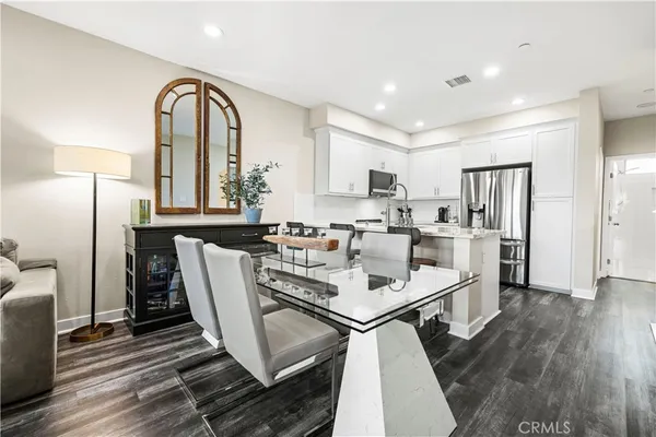 a kitchen with stainless steel appliances a dining table chairs refrigerator and sink