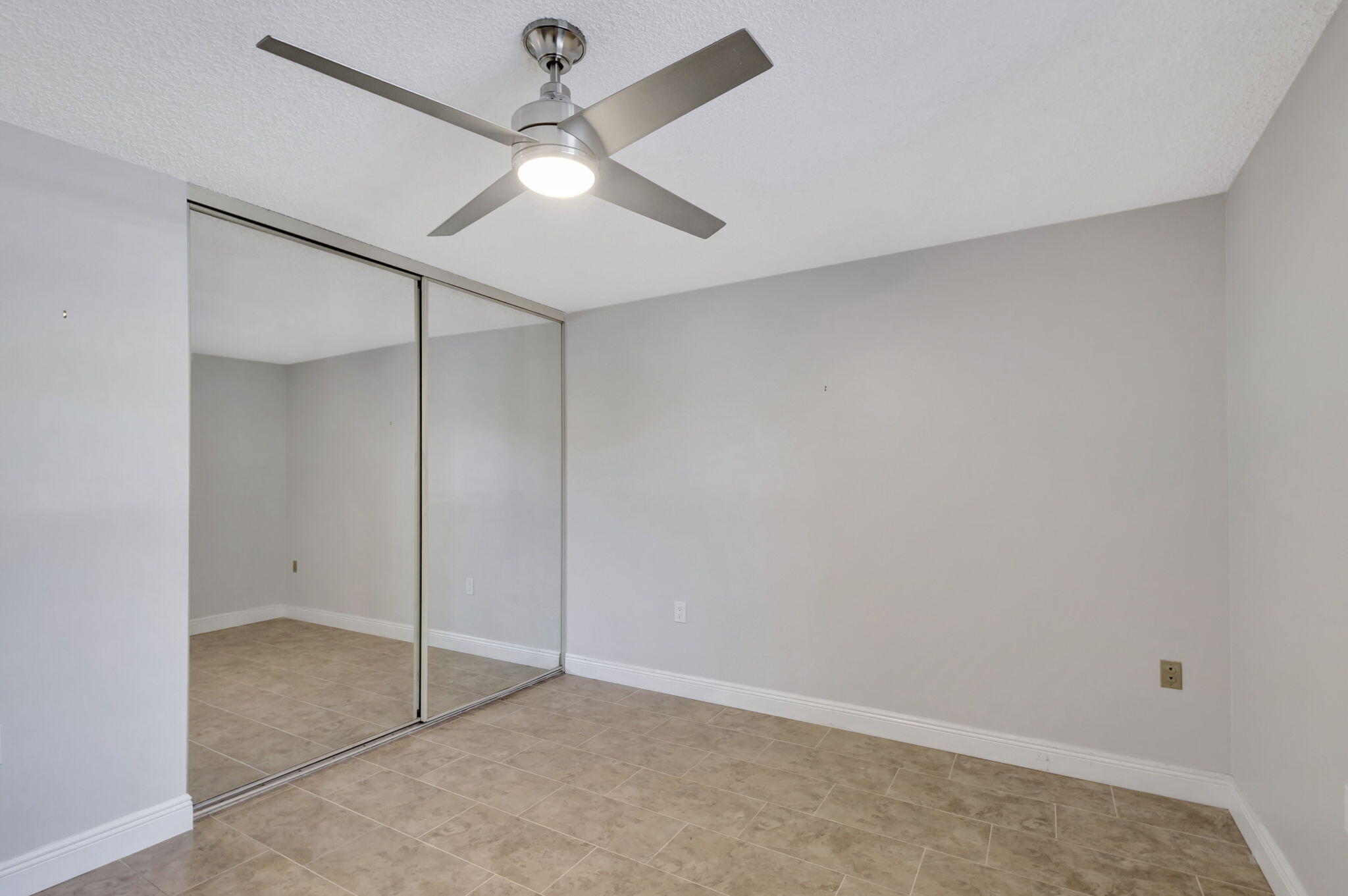 2741 Village Boulevard, Unit 104 West Palm Beach, FL 33409 - Photo 19 of 37 an empty room with a ceiling fan and a window