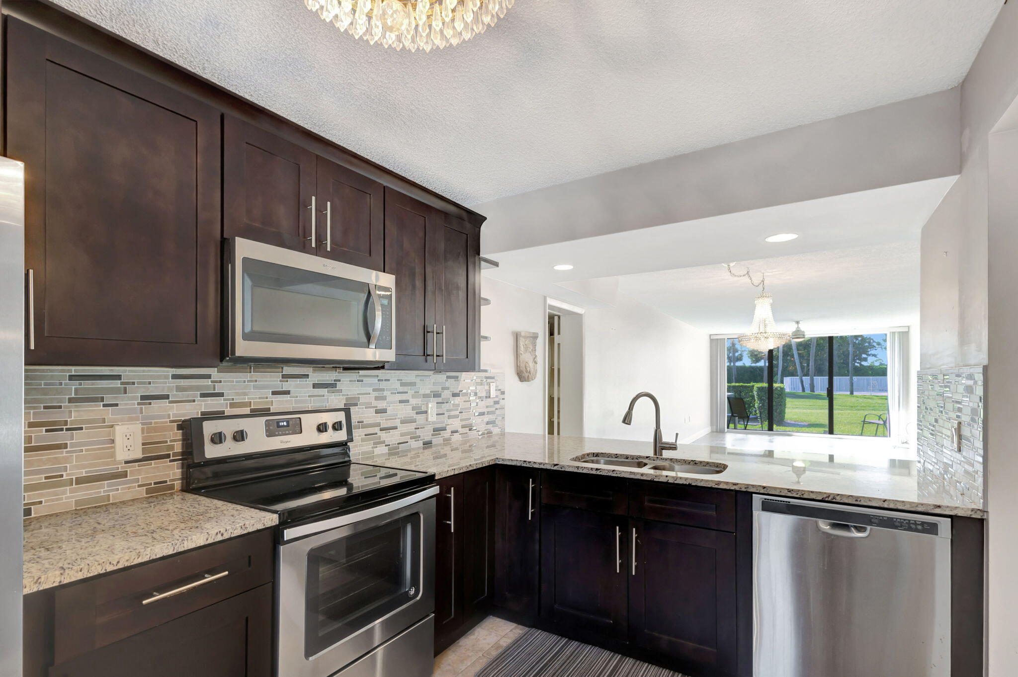 2741 Village Boulevard, Unit 104 West Palm Beach, FL 33409 - Photo 2 of 37 a kitchen with stainless steel appliances granite countertop a stove microwave and sink