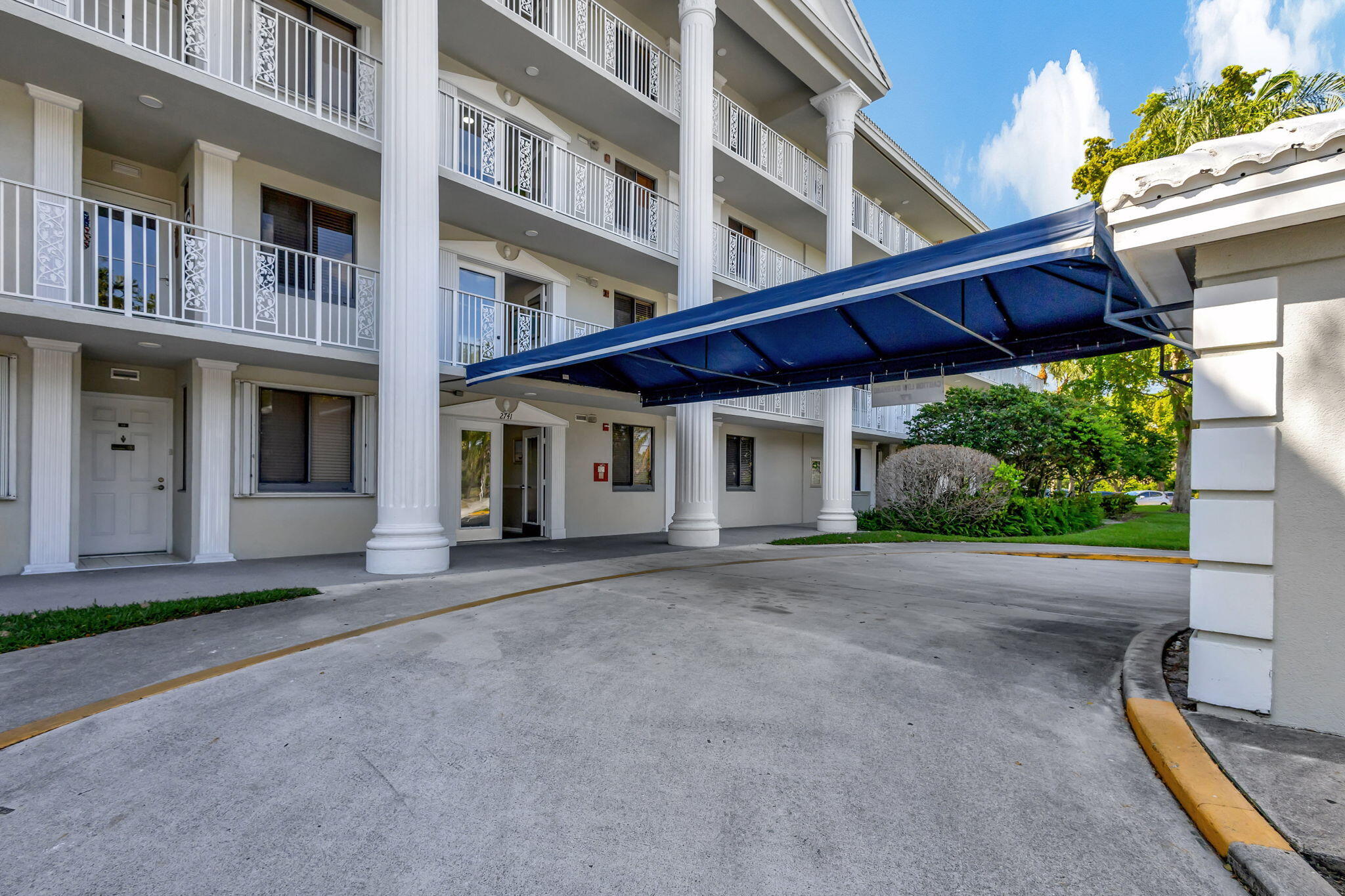 2741 Village Boulevard, Unit 104 West Palm Beach, FL 33409 - Photo 34 of 37 a front view of a building with a yard