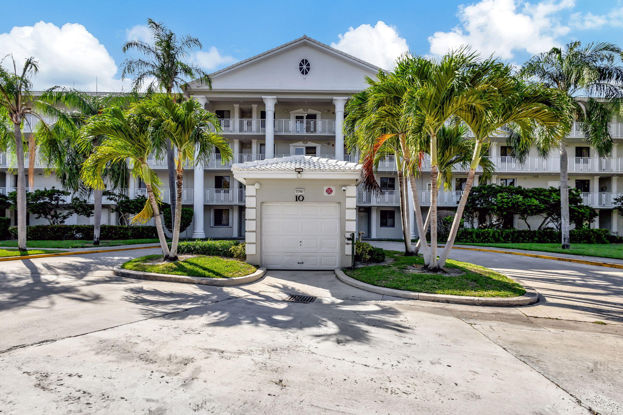 2741 Village Boulevard, Unit 104 West Palm Beach, FL 33409 - Photo 35 of 37 a front view of a house with a yard and palm trees