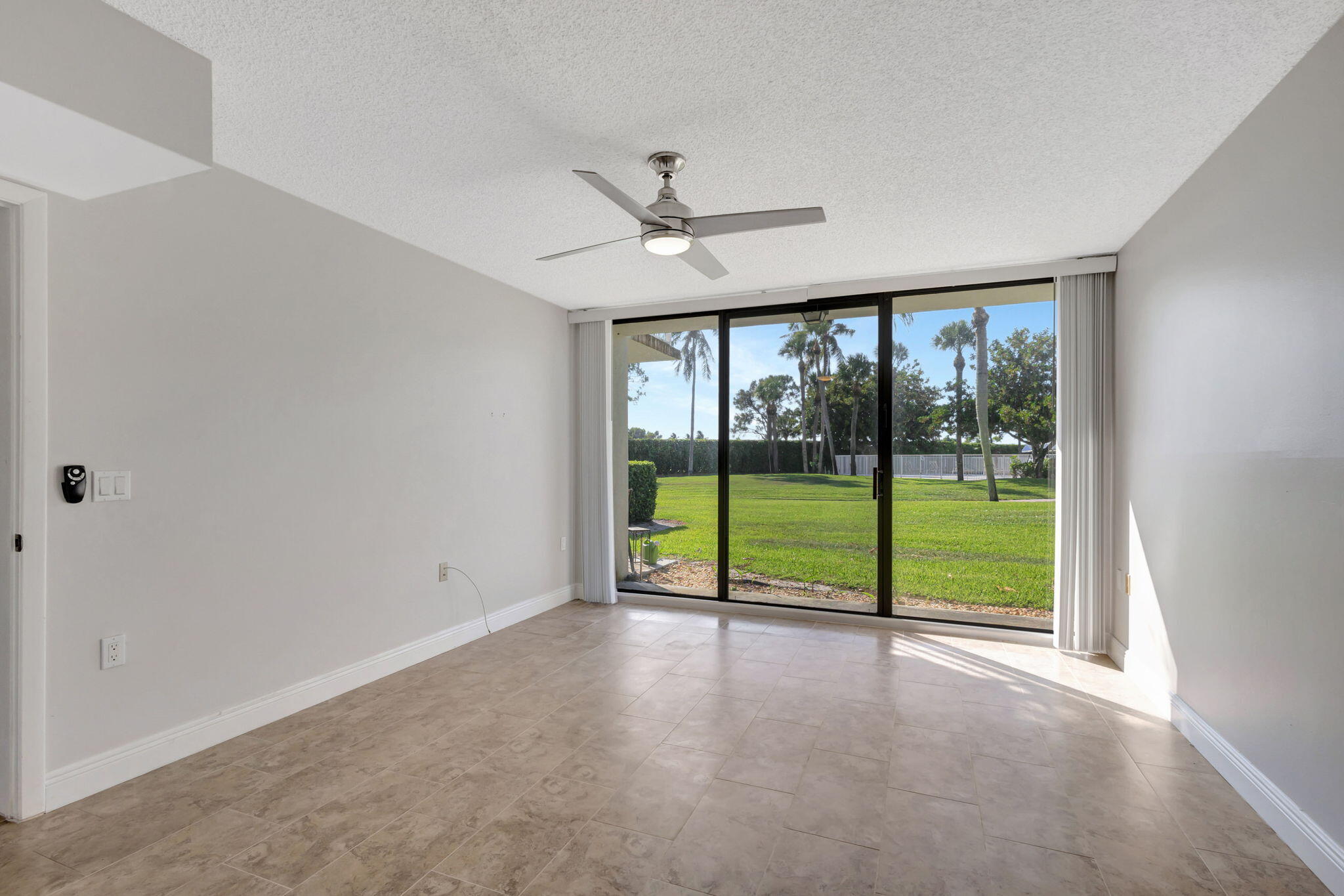 2741 Village Boulevard, Unit 104 West Palm Beach, FL 33409 - Photo 9 of 37 an empty room with chandelier fan windows and outdoor view