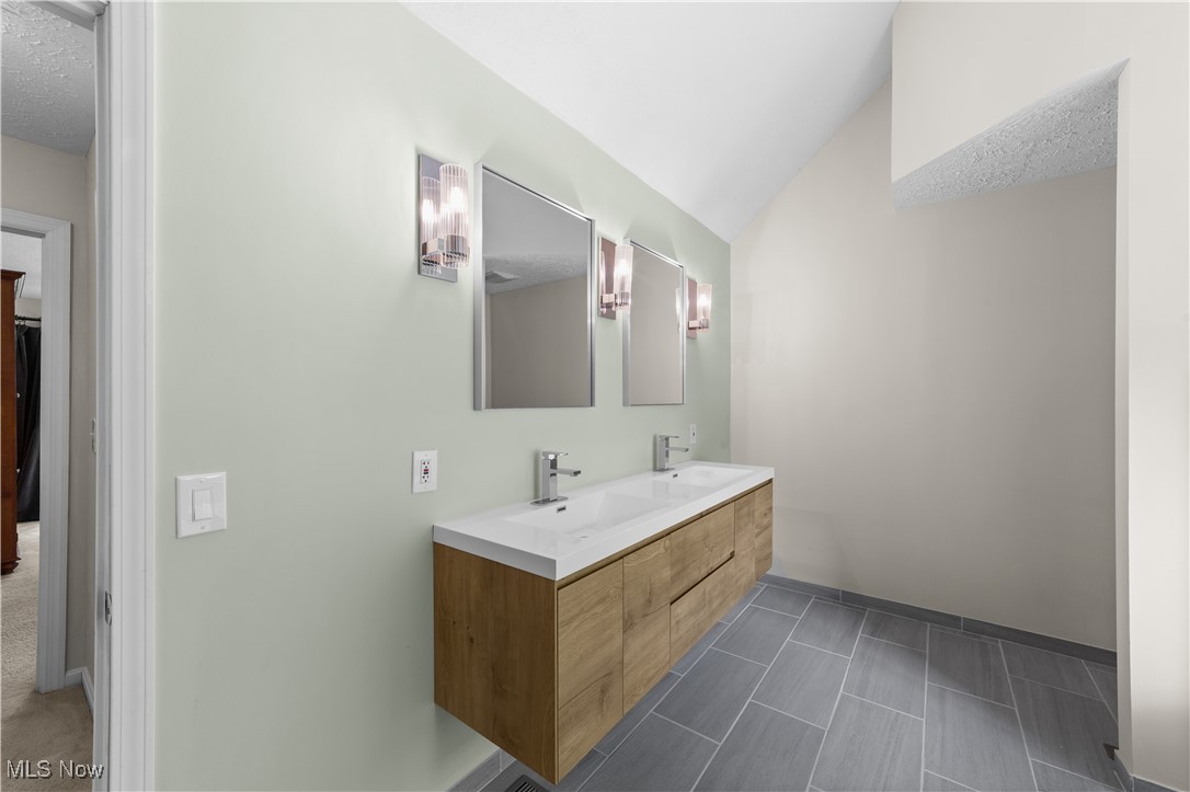 30825 Cannon Road Solon, OH 44139 - Photo 24 of 49 Bathroom featuring double vanity, lofted ceiling, and a textured ceiling