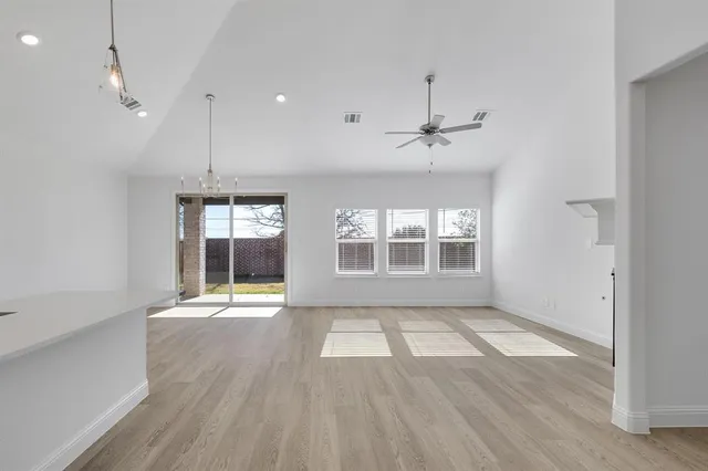 an empty room with wooden floor a ceiling fan and windows