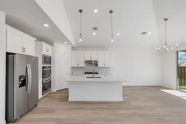 a view living room with stainless steel appliances kitchen island granite countertop a refrigerator a stove a sink and a oven